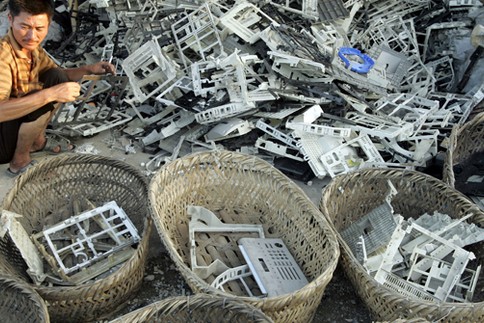 man_in_asian_landfill_surrounded_by_electronic_waste